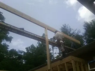 Carpenter setting a ridge beam over a new addition frame — Ice Dam Removal by Roofing Brothers in Ebony