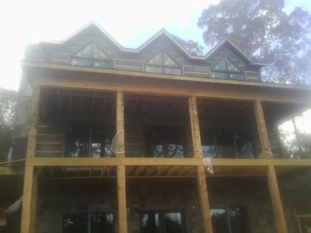 Dormers and porch framing on a large log home under construction — Roof Coating work by our crew in Ebony