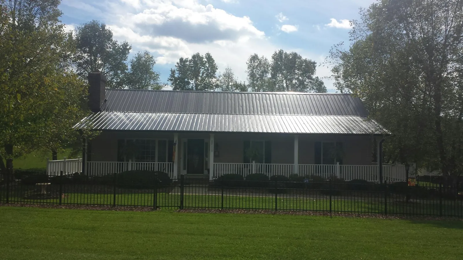 Gray metal roof on a brick ranch with a full width front porch — Gutter Guard Installation work by our crew in Ebony