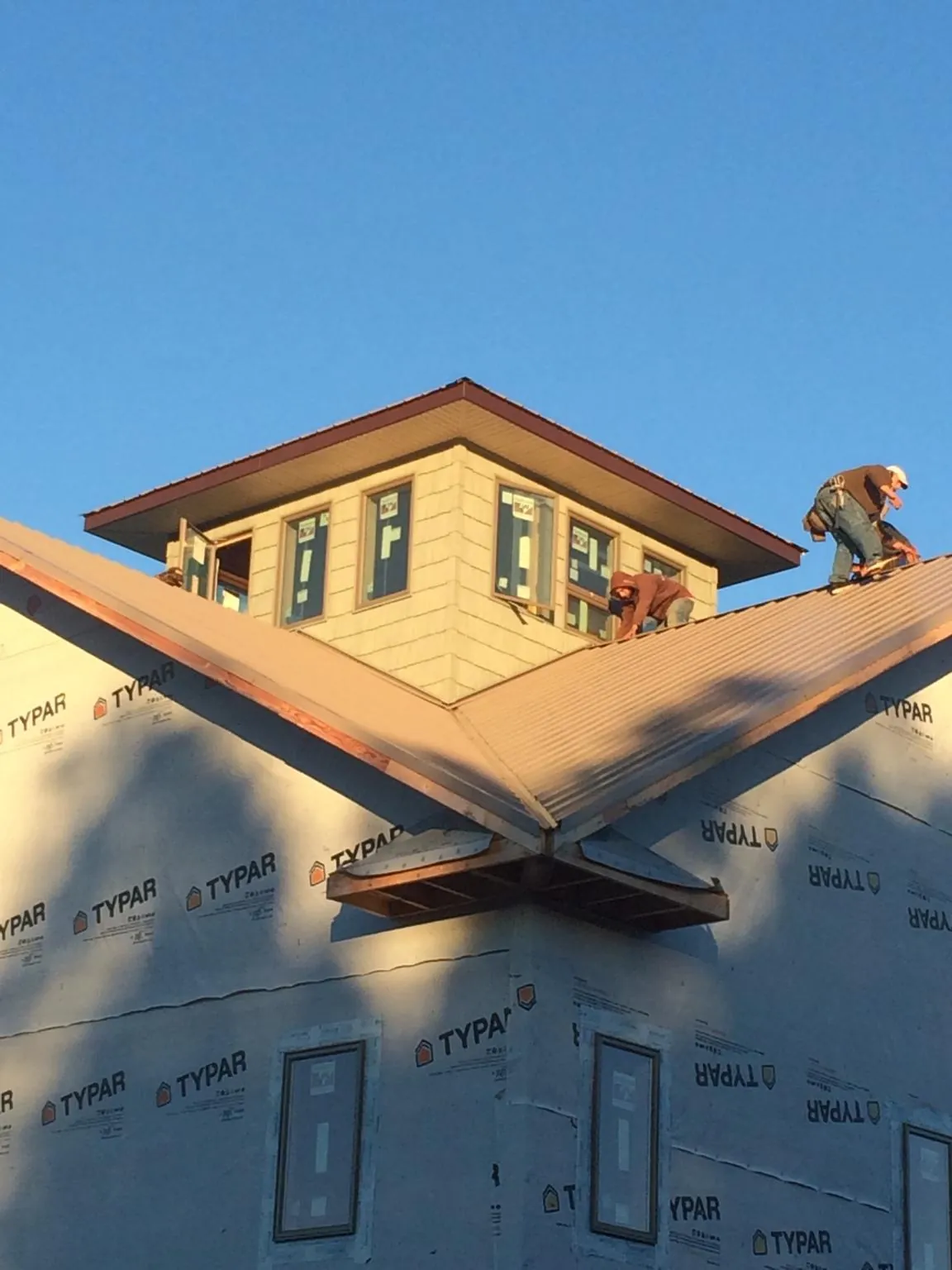 Roofers working around a rooftop cupola on a new metal roof at sunset — Roof Waterproofing in Ebony by Roofing Brothers